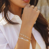 Model wearing IGGI Coffee Bean Bracelet stacked with other gold bracelets and rings