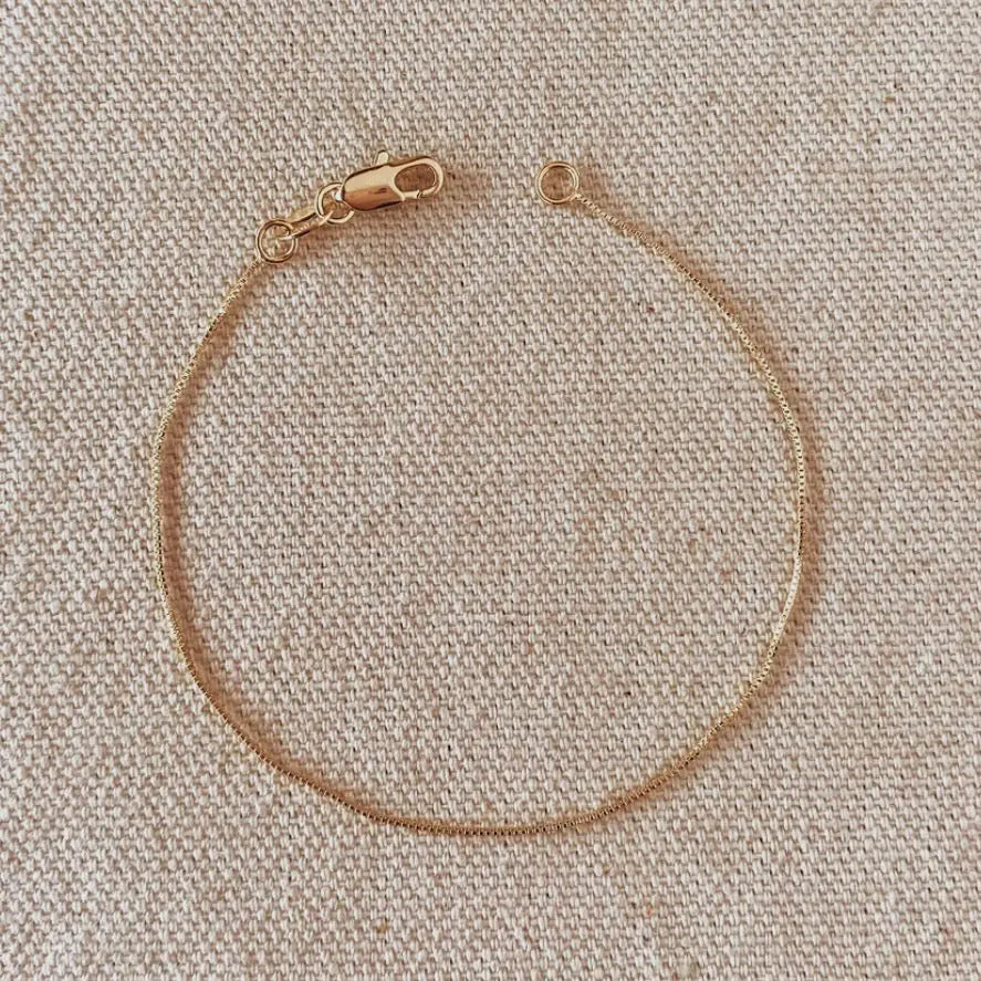 Full view of the Dainty Box Chain Bracelet on neutral fabric, gold-filled with lobster clasp