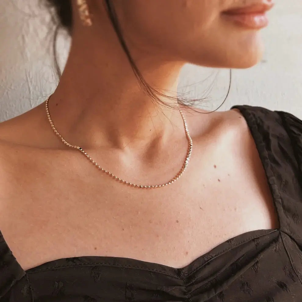 Close-up of Dotted Chain Necklace layered with other IGGI gold necklaces on model’s neck