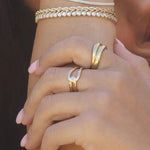 Close-up of Gwen Ring in 18k gold-filled worn on hand, paired with layered gold bracelets, captured in natural sunlight