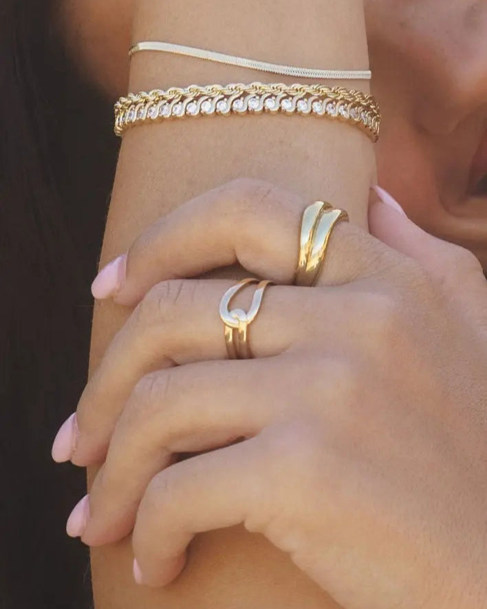 Close-up of Gwen Ring in 18k gold-filled worn on hand, paired with layered gold bracelets, captured in natural sunlight