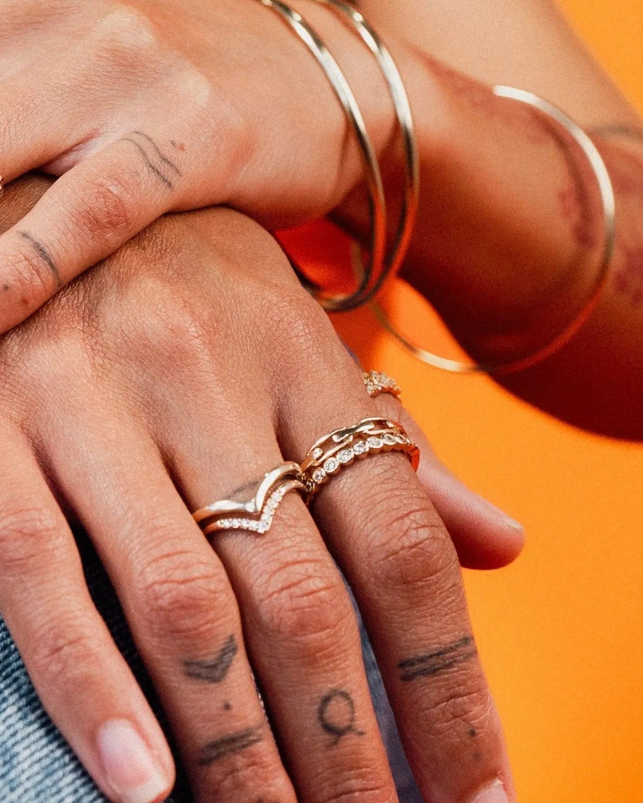 Close-up of hands wearing the Harlow Ring stacked with other gold rings and bangles by IGGI Jewellery