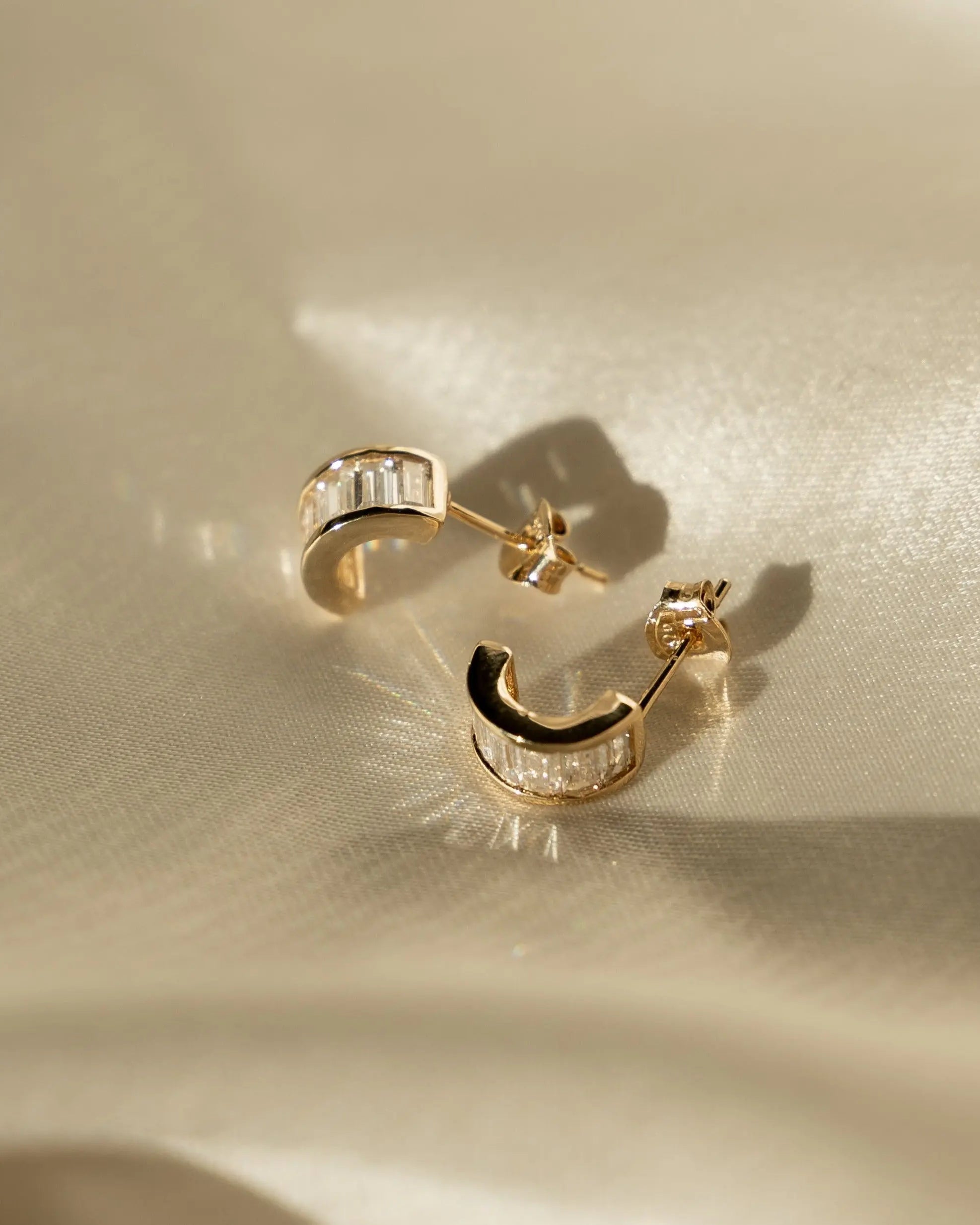 Sonia Studs gold-filled hoop earrings with baguette CZ stones displayed on satin fabric