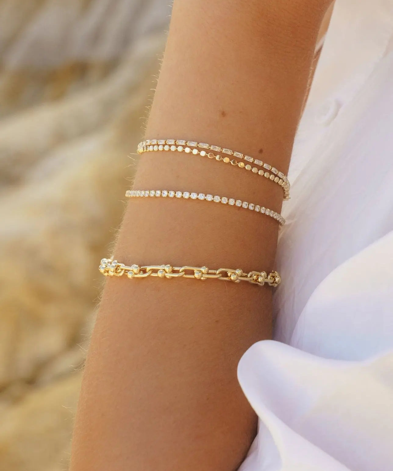 Close-up of IGGI Jewellery chunky link chain bracelet stacked with delicate gold chains on wrist.