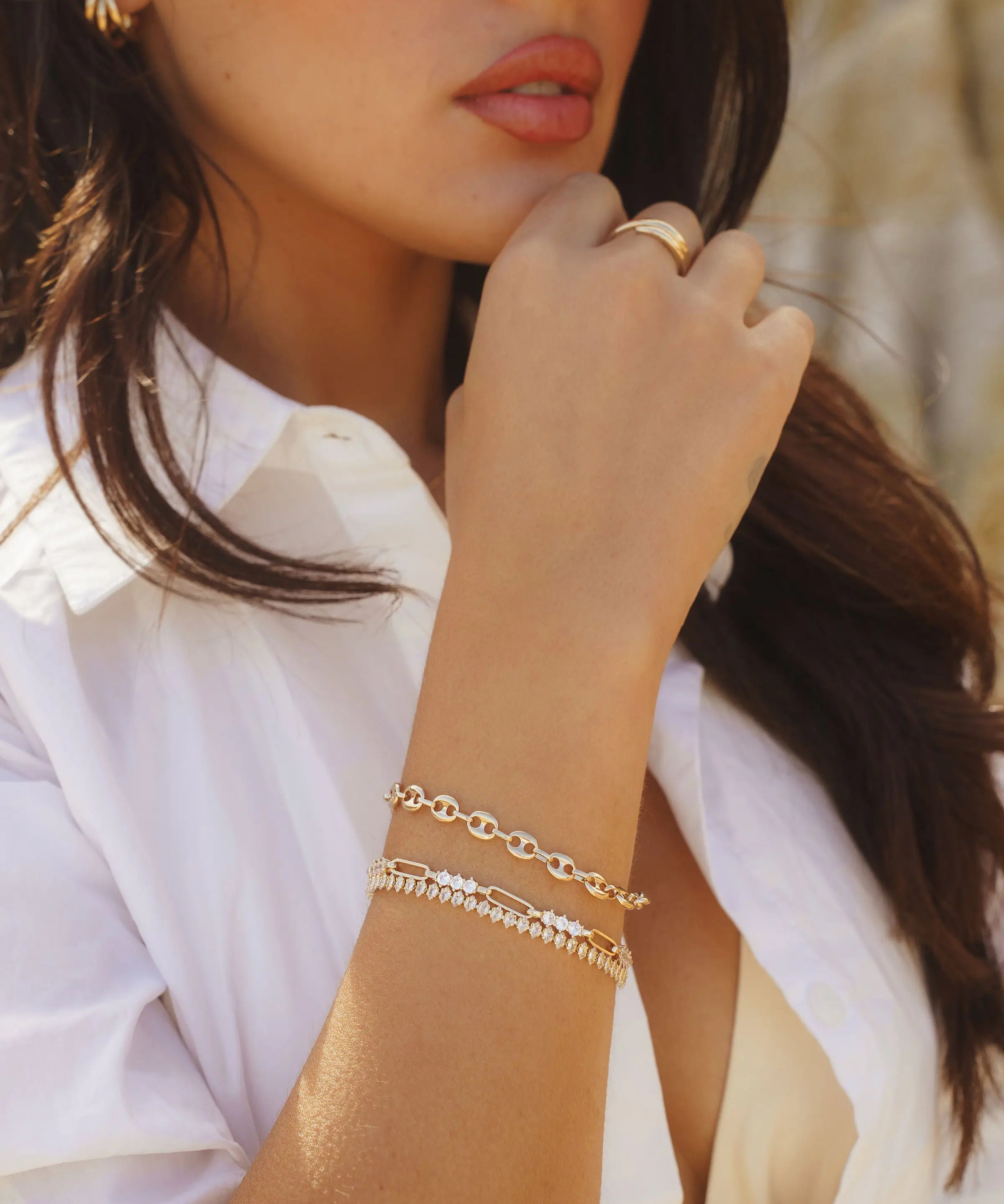 Model wearing IGGI Coffee Bean Bracelet stacked with other gold bracelets and rings