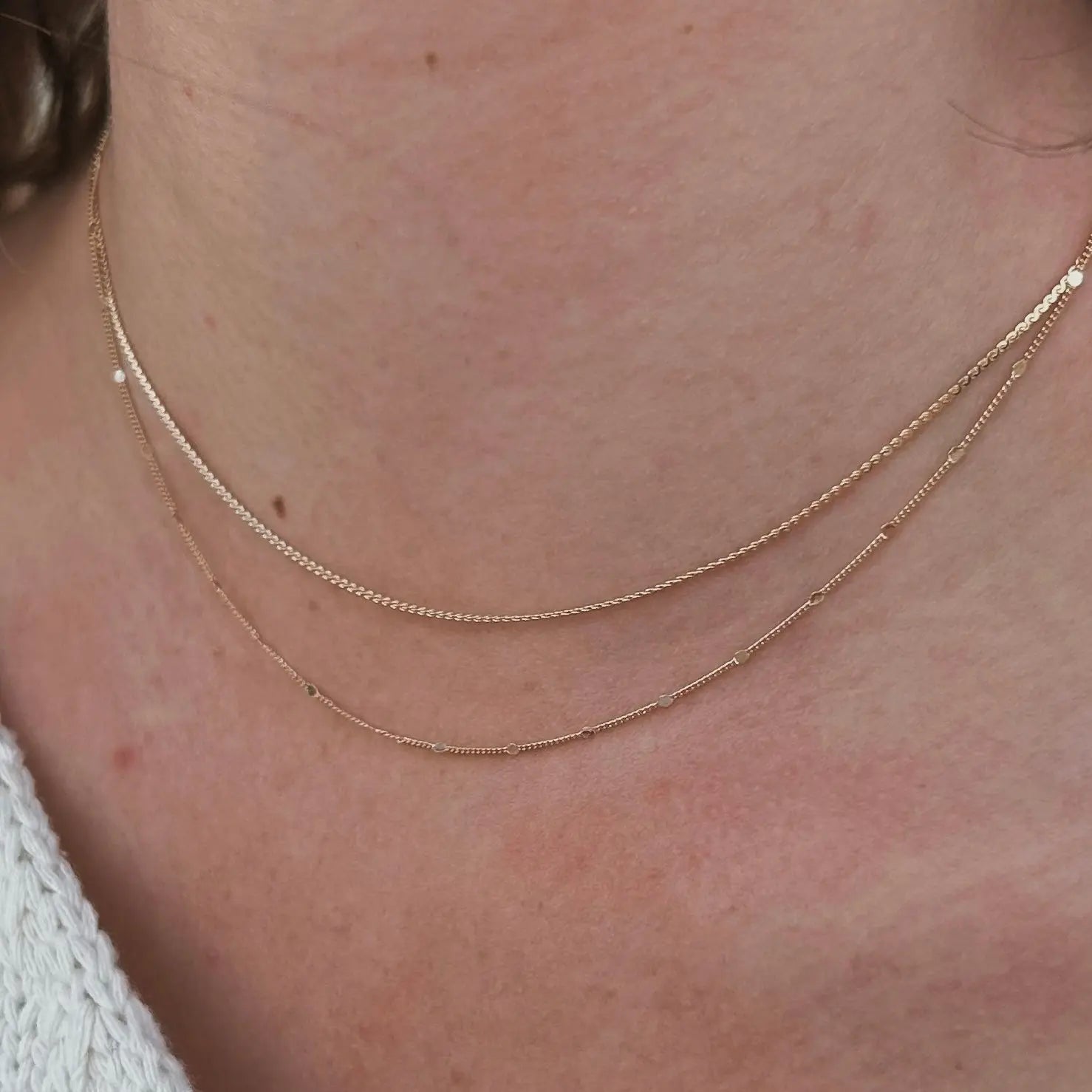 Model wearing Curb Pressed Chain Necklace layered with other gold chains outdoors