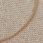 Dainty Box Chain Bracelet laid flat on woven fabric, showcasing box-style links