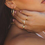 Model wearing the Demi Ring stacked with other gold rings and hoop earrings