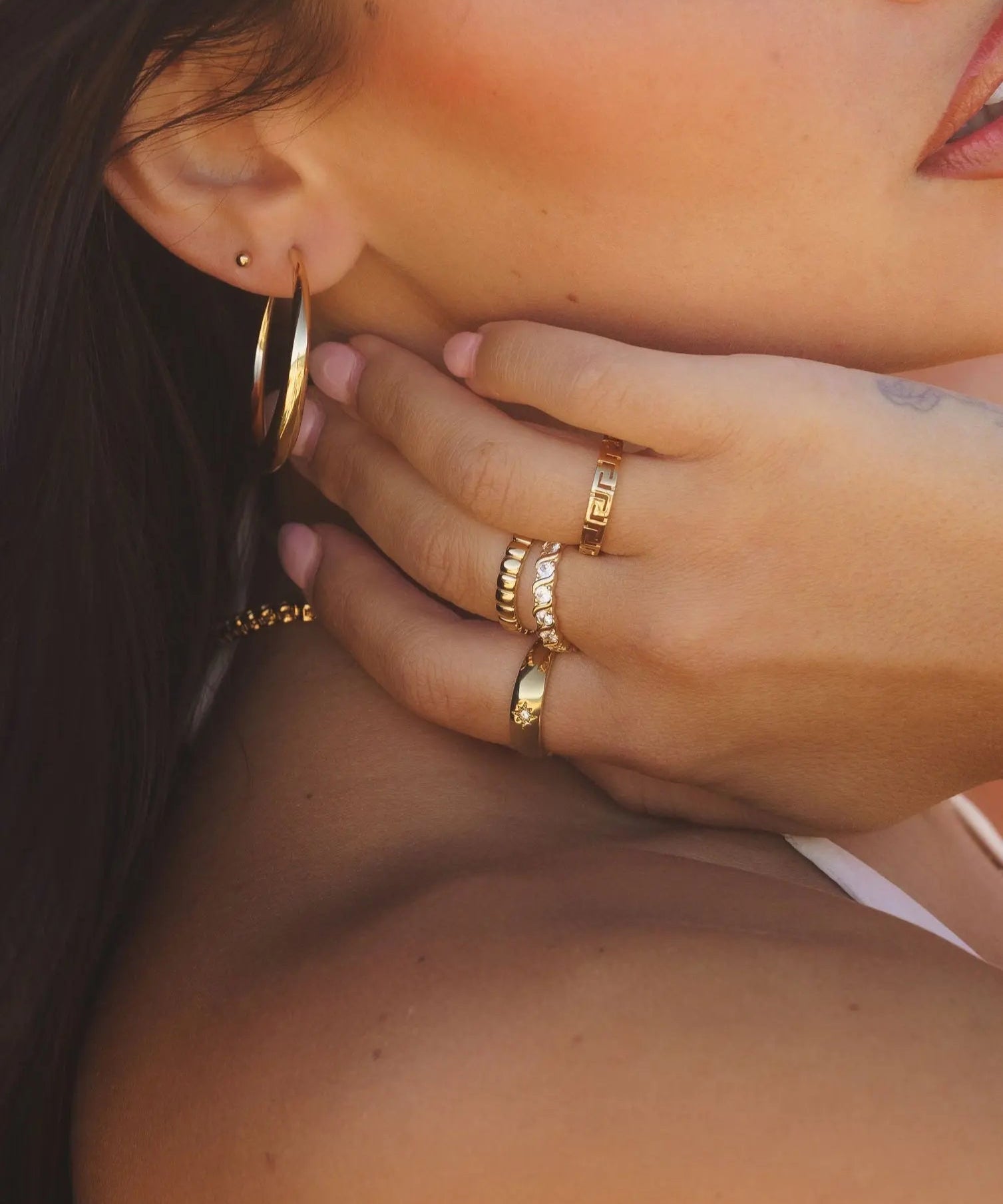Model wearing the Demi Ring stacked with other gold rings and hoop earrings