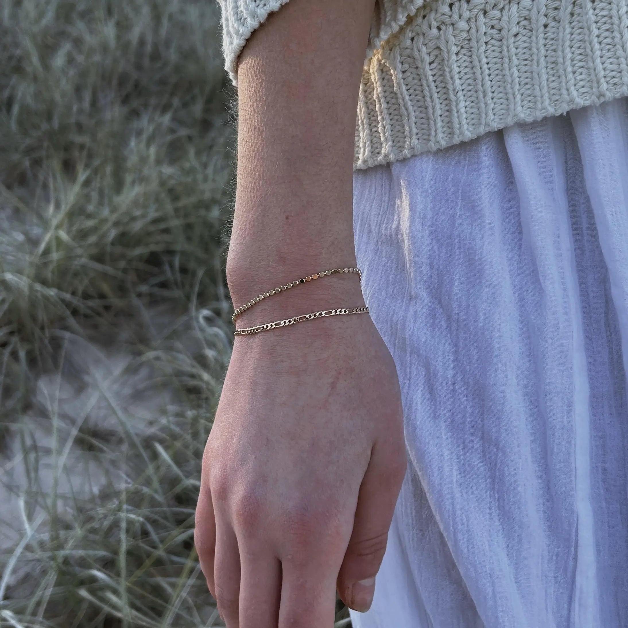 Close-up of a hand wearing a gold bracelet with a natural background