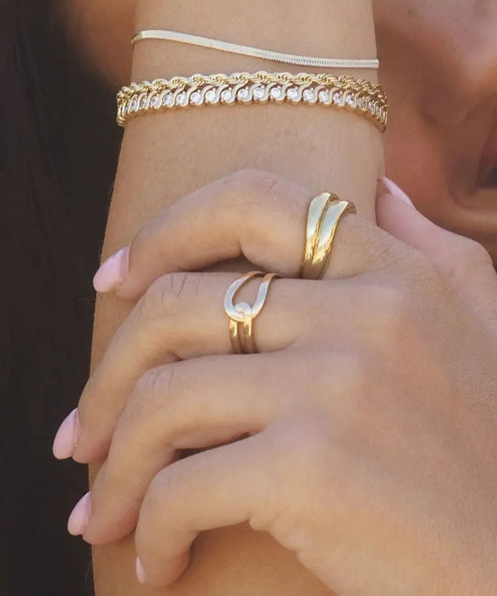 Close-up of Gwen Ring in 18k gold-filled worn on hand, paired with layered gold bracelets, captured in natural sunlight