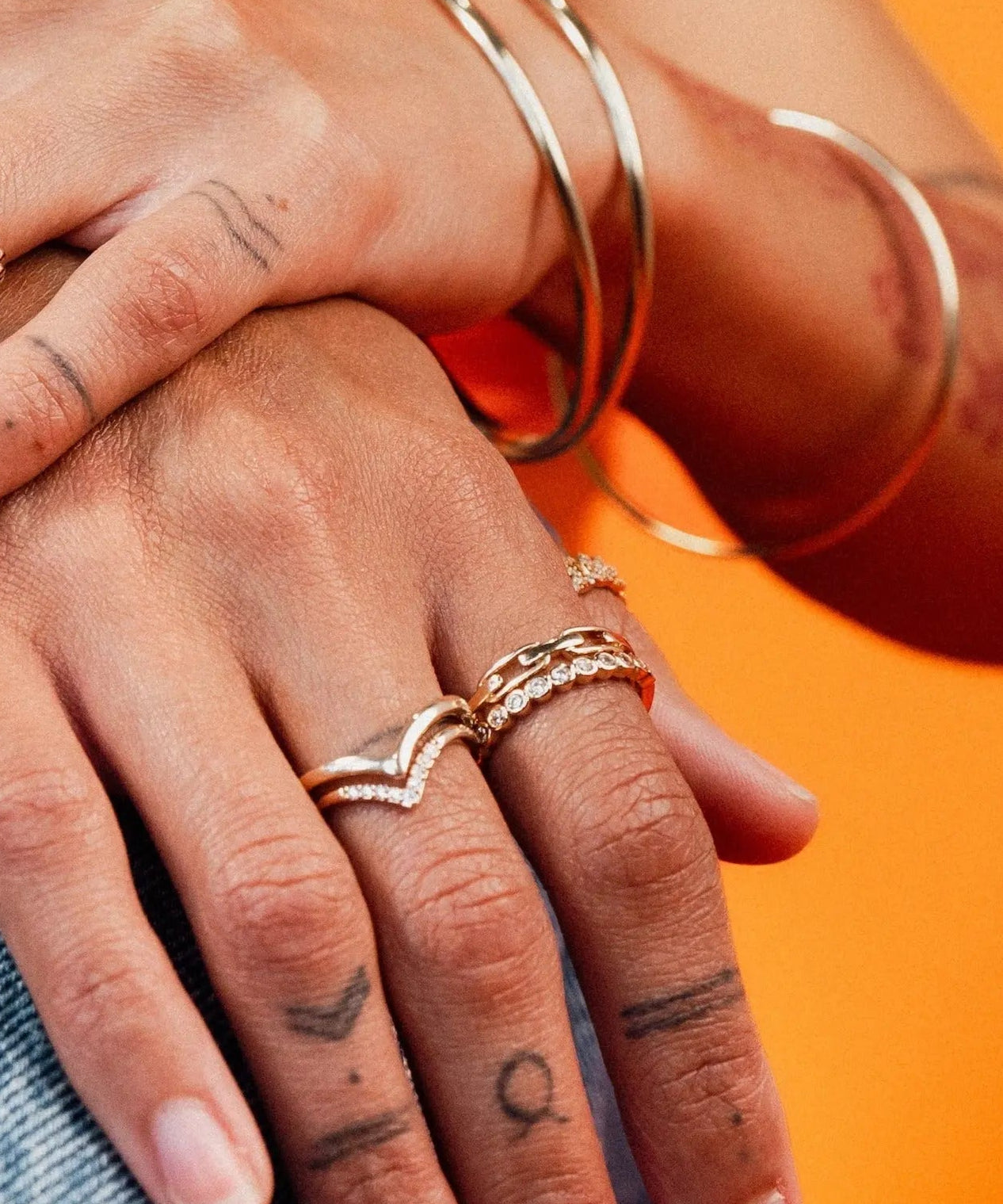 Close-up of hands wearing the Harlow Ring stacked with other gold rings and bangles by IGGI Jewellery