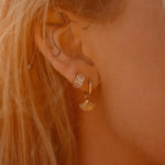 Model wearing Heka Hoops 18k gold-filled earrings with fan-shaped charm