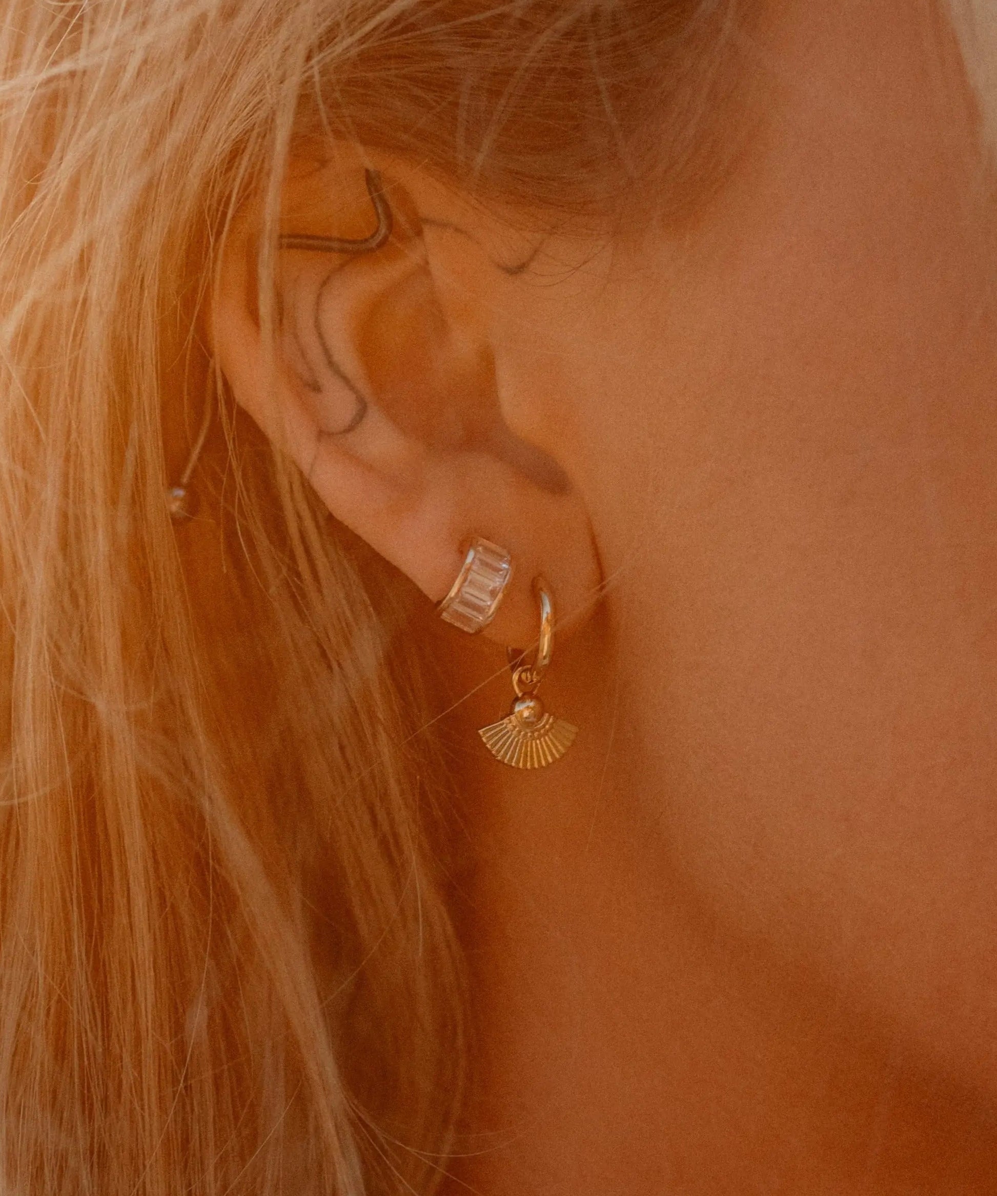 Model wearing Heka Hoops 18k gold-filled earrings with fan-shaped charm