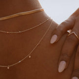 Close-up of IGGI Jewellery Star Drop Necklace in 18k gold-filled, layered with gold chains and styled on model’s neckline in warm natural light