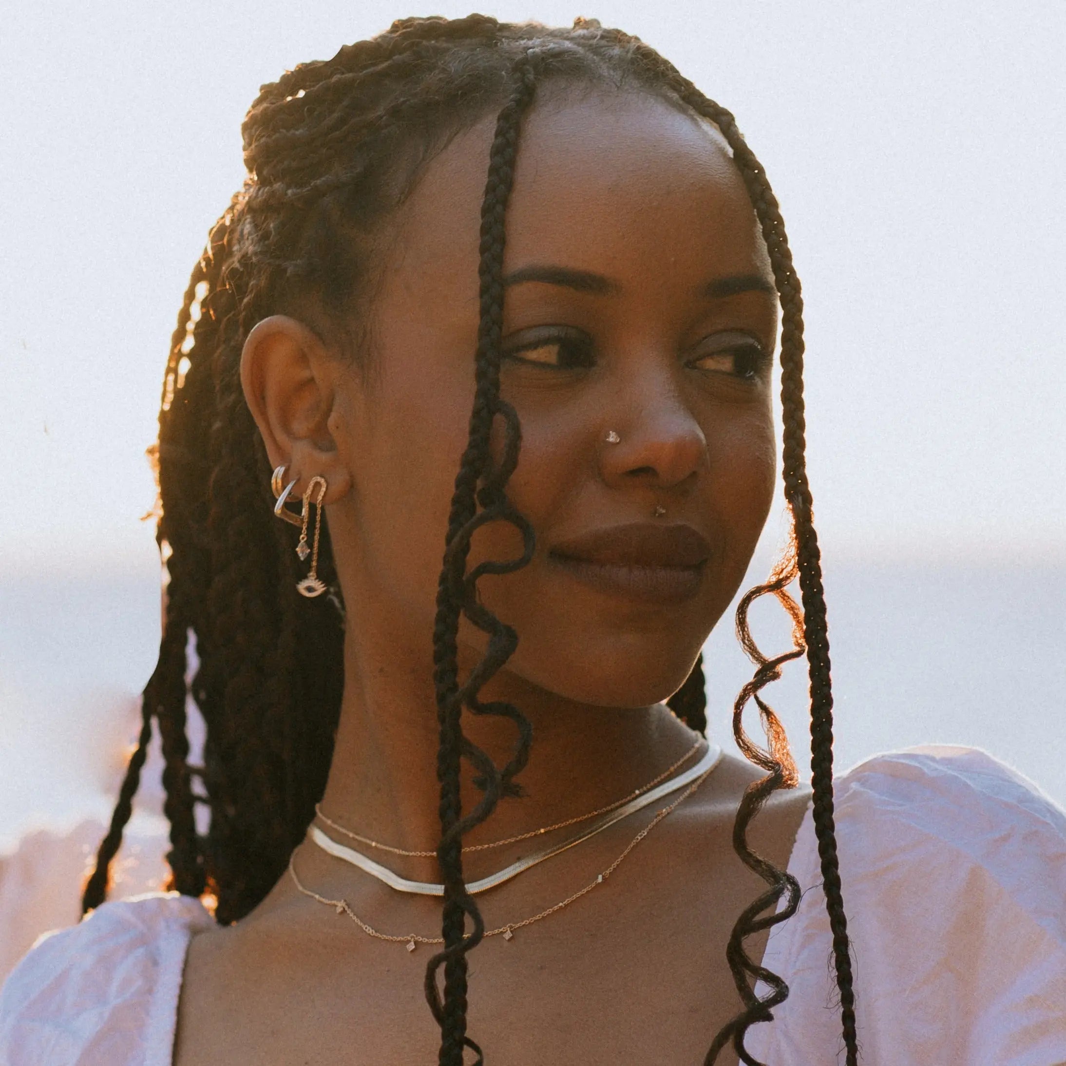 Model wearing IGGI Jewellery Star Drop Necklace in 18k gold-filled, layered with gold chains, photographed outdoors in natural sunlight